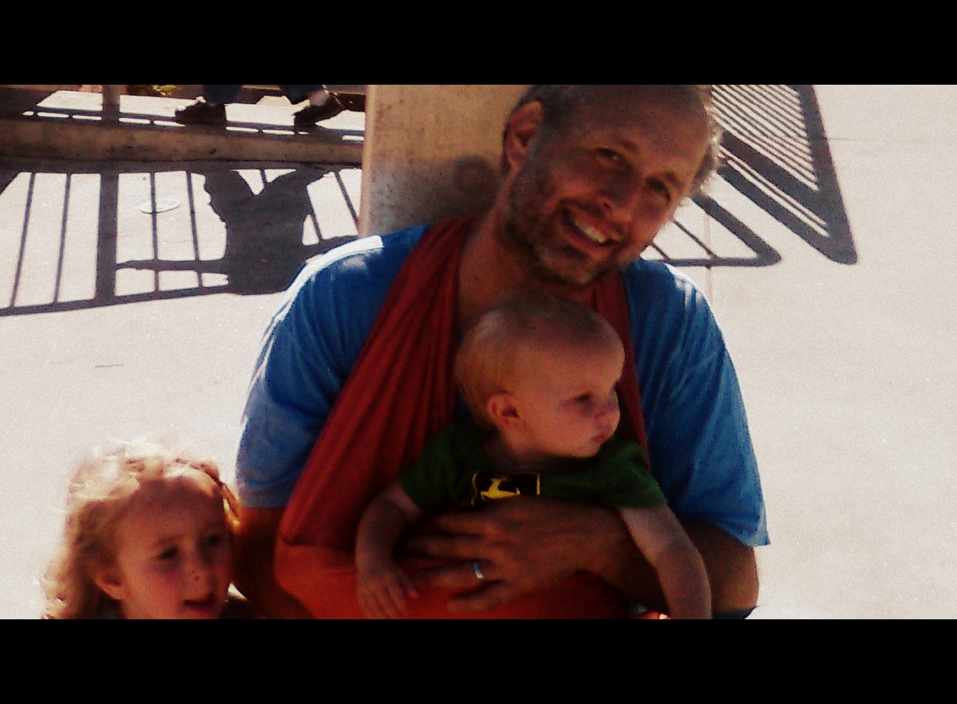 Author and a kid in a wrap sitting outside Balboa Park BART station in San Francisco